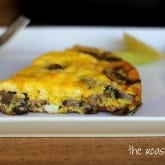 A slice of mushroom frittata with visible mushrooms sits on a white plate, accompanied by a small wedge of green apple. A fork rests in the background. The words the roasted root appear in the corner.