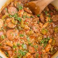 Large green pot of finished Jambalaya with a blue striped napkin to the side