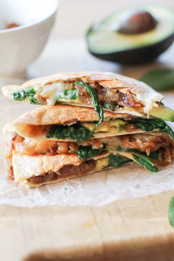 Stack of quesadillas with cheese, onion, spinach, and avocado.