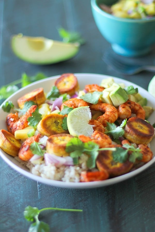 A vibrant Cuban Shrimp Bowl filled with rice, grilled shrimp, fried plantains, avocado chunks, pineapple, red onion, fresh cilantro, and a lime wedge—all arranged in a colorful, appetizing presentation.