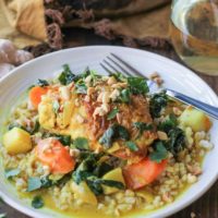 bowl of braised chicken with sauce and veggies and a fork