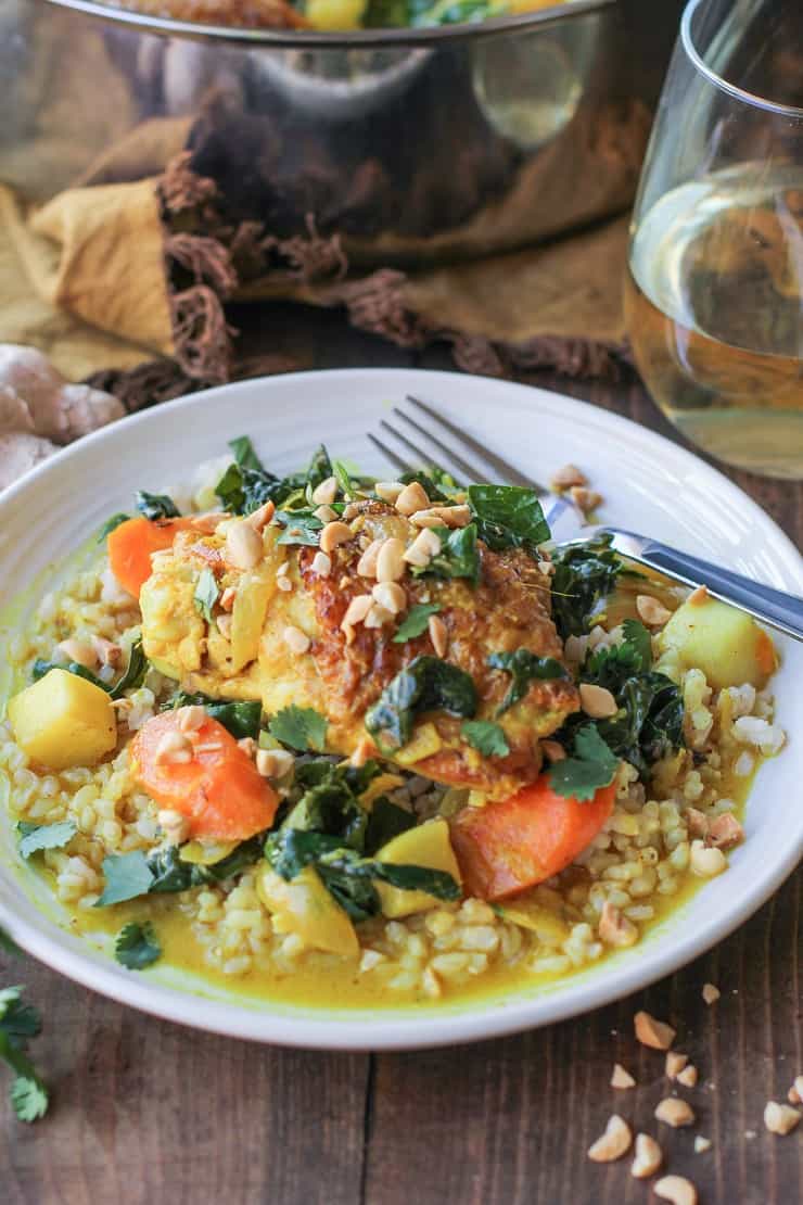 bowl of braised chicken with sauce and veggies and a fork