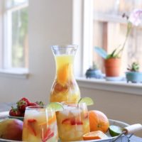 Two glasses and a pitcher of tropical white sangria