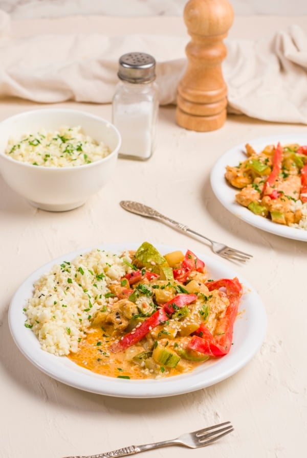 Two bowls of Thai red curry with chicken and vegetables, served with cauliflower rice.