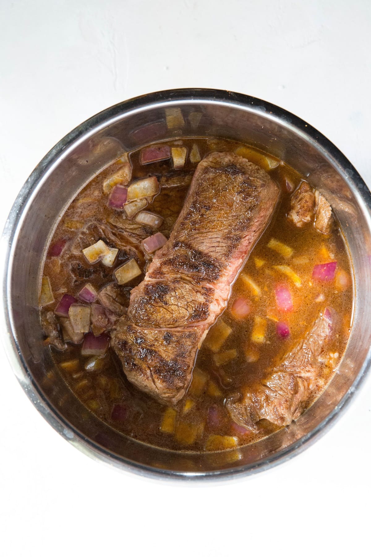 Seared beef, onion and broth in an Instant Pot to make pressure cooker shredded beef.