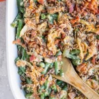Top down image of a large casserole dish filled with healthy green bean casserole with caramelized onions and bacon on top.