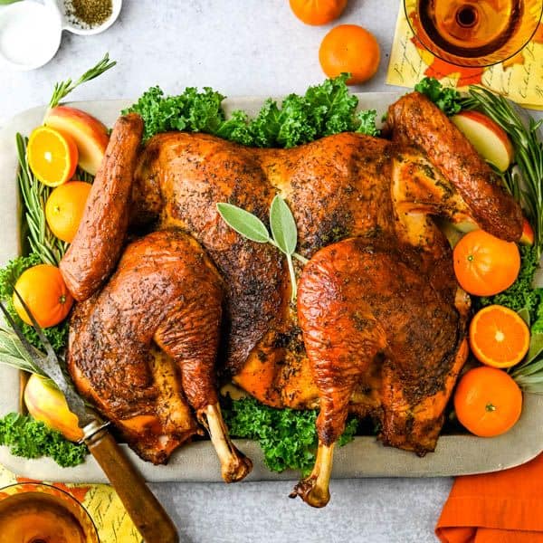 Spatchcook Grilled Turkey with Cider Gravy from Garlic and Zest - Want a delicious, super-moist turkey that doesnโt require a 5 gallon brining bucket? This easyย dry brine turkey is the answer. Instead of soaking inย liquid brine, an easyย 4-ingredient turkey rubย infuses the bird with flavor and moisture โ and all you need is a sheetย pan. Plus, this birdย ย cooks in about half the time.