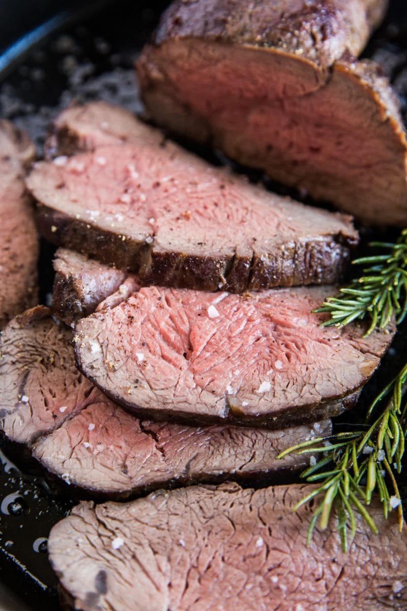 Medium-rare beef tenderloin sliced into slices in a cast iron skillet