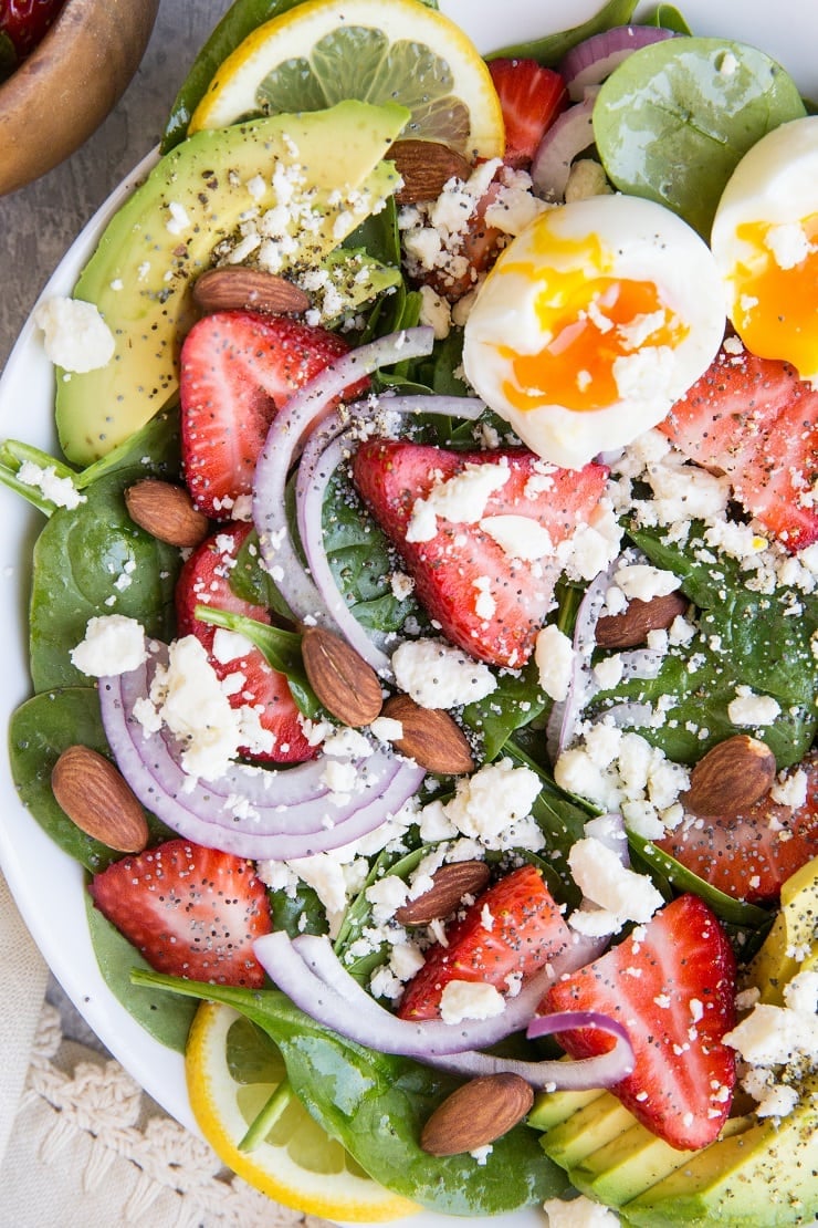 Strawberry Spinach Salad with Poppy Seed Dressing, jammy egg, avocado, roasted almonds, feta, and red onion! A beautiful, delicious salad recipe for any gathering! Amazing side dish or main entrรฉe.