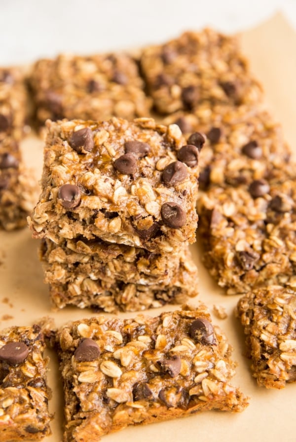 Stack of oatmeal bars sitting on parchment paper with oatmeal bars to the side