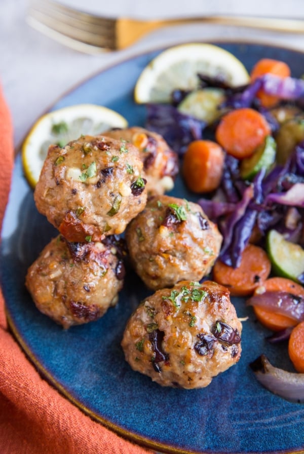 Mediterranean meatballs on a blue plate next to sautéed vegetables