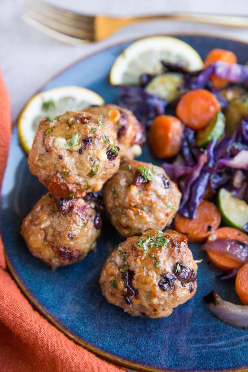 Mediterranean meatballs on a blue plate next to sautรฉed vegetables