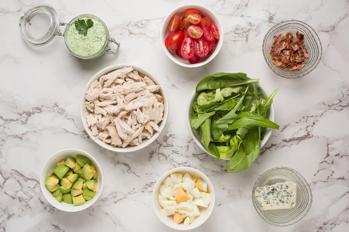 Ingredients for Cobb Salad laid out on a marble surface.
