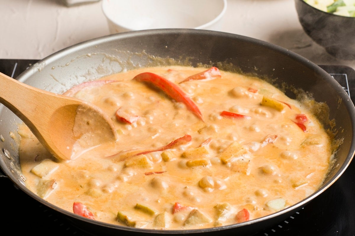 Creamy red curry sauce in a skillet with vegetables
