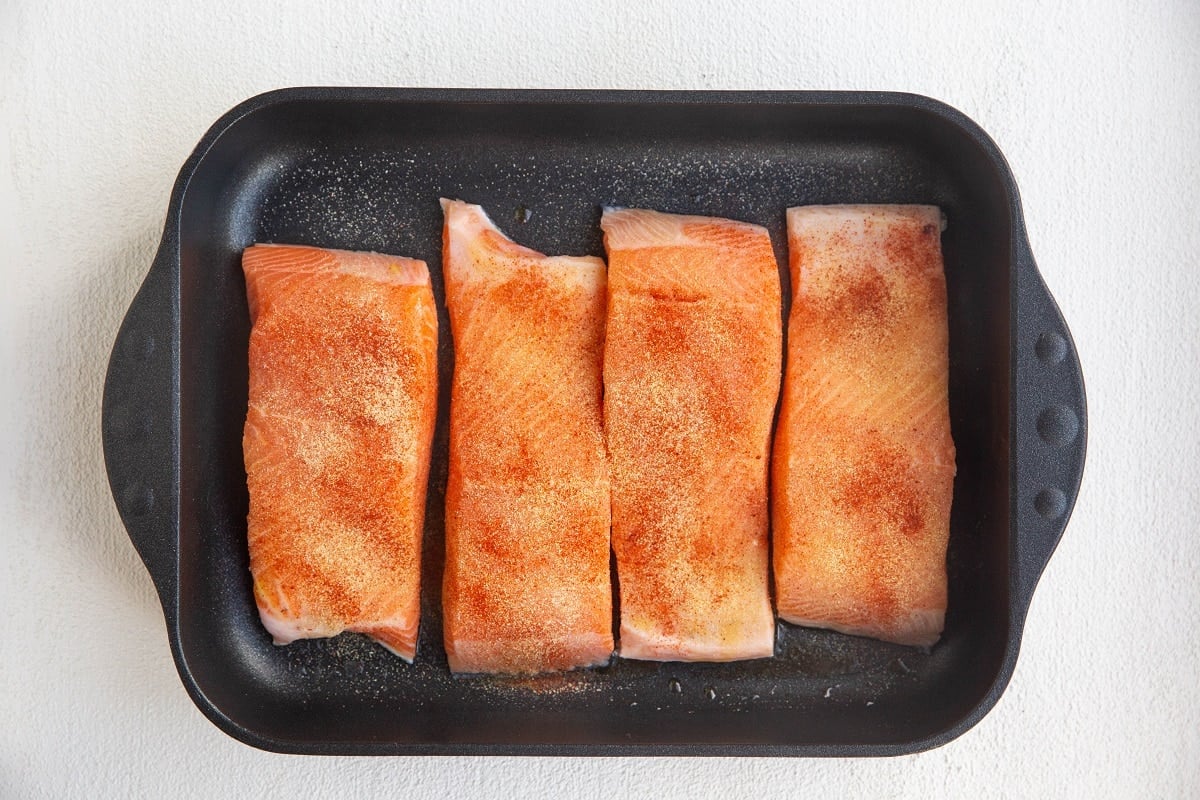 Salmon sprinkled with seasonings in a casserole dish.