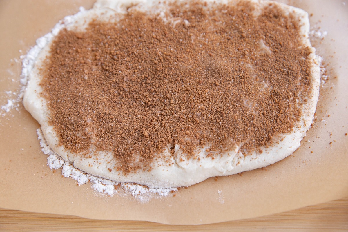 Cinnamon roll dough sprinkled with cinnamon and sugar, ready to be rolled