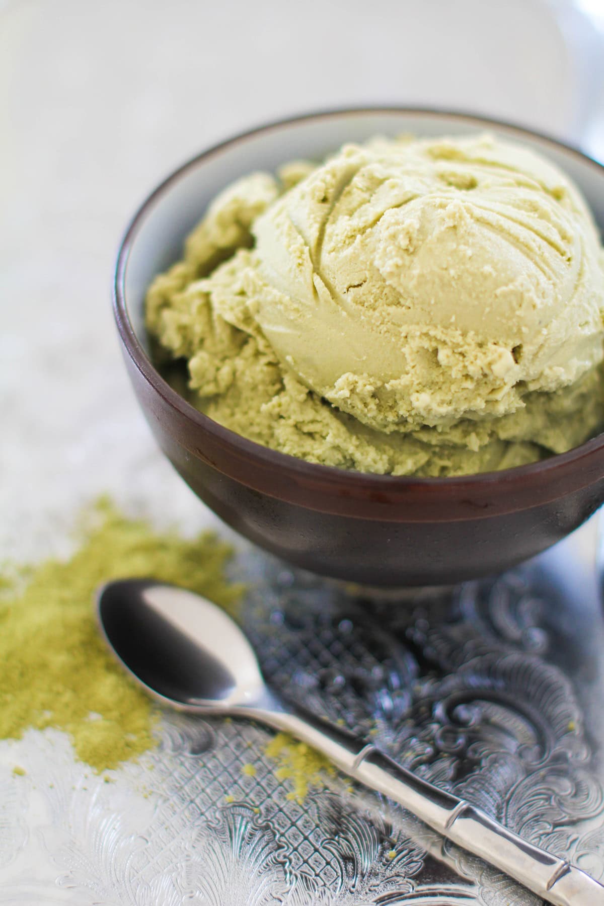 Scoop of green tea matcha coconut milk ice cream in a bowl with a spoon to the side.