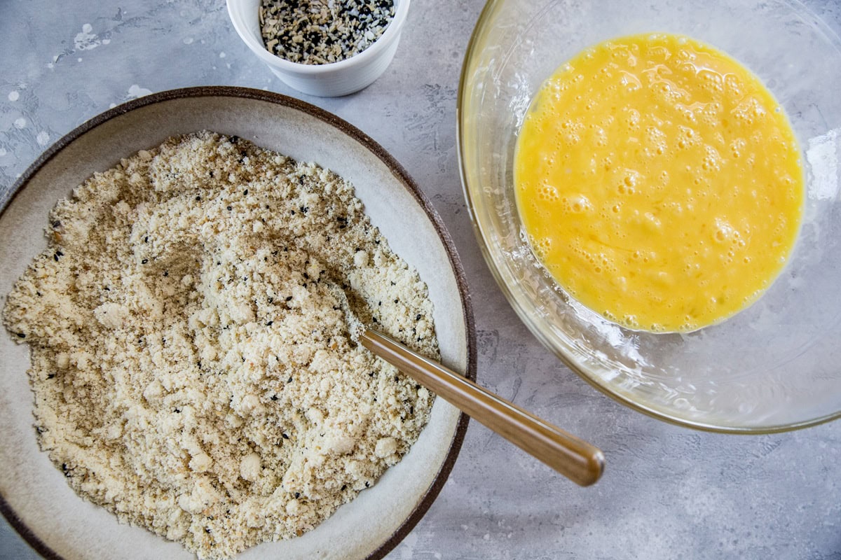 Mixing bowl full of dry ingredients and a mixing bowl of wet ingredients to the side.