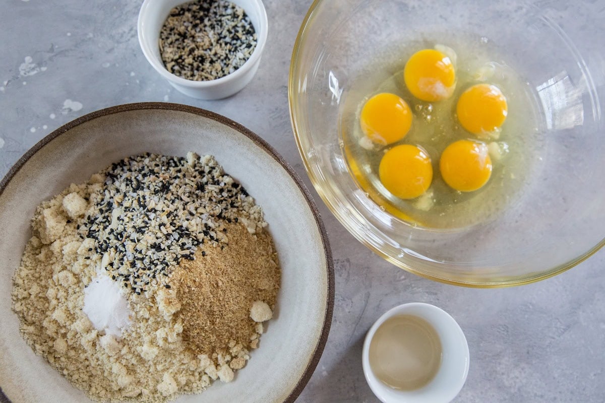 Large mixing bowl full of dry ingredients. Another mixing bowl to the side with eggs, waiting to be whisked together.