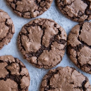 Chocolate cookies sitting on a backdrop, ready to eat. The cookies are crinkly like classic crinkle cookies.