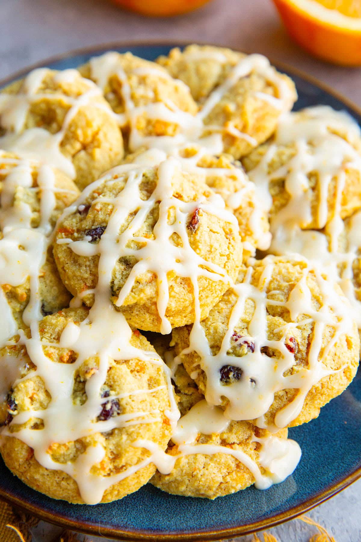 Blue plate full of cranberry orange cookies drizzled with orange glaze, ready to eat.