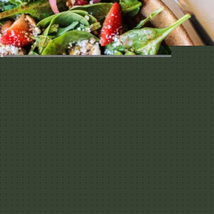 Bug wooden bowl of arugula salad with pickled red onions, feta cheese, avocado, strawberries and strawberry vinaigrette