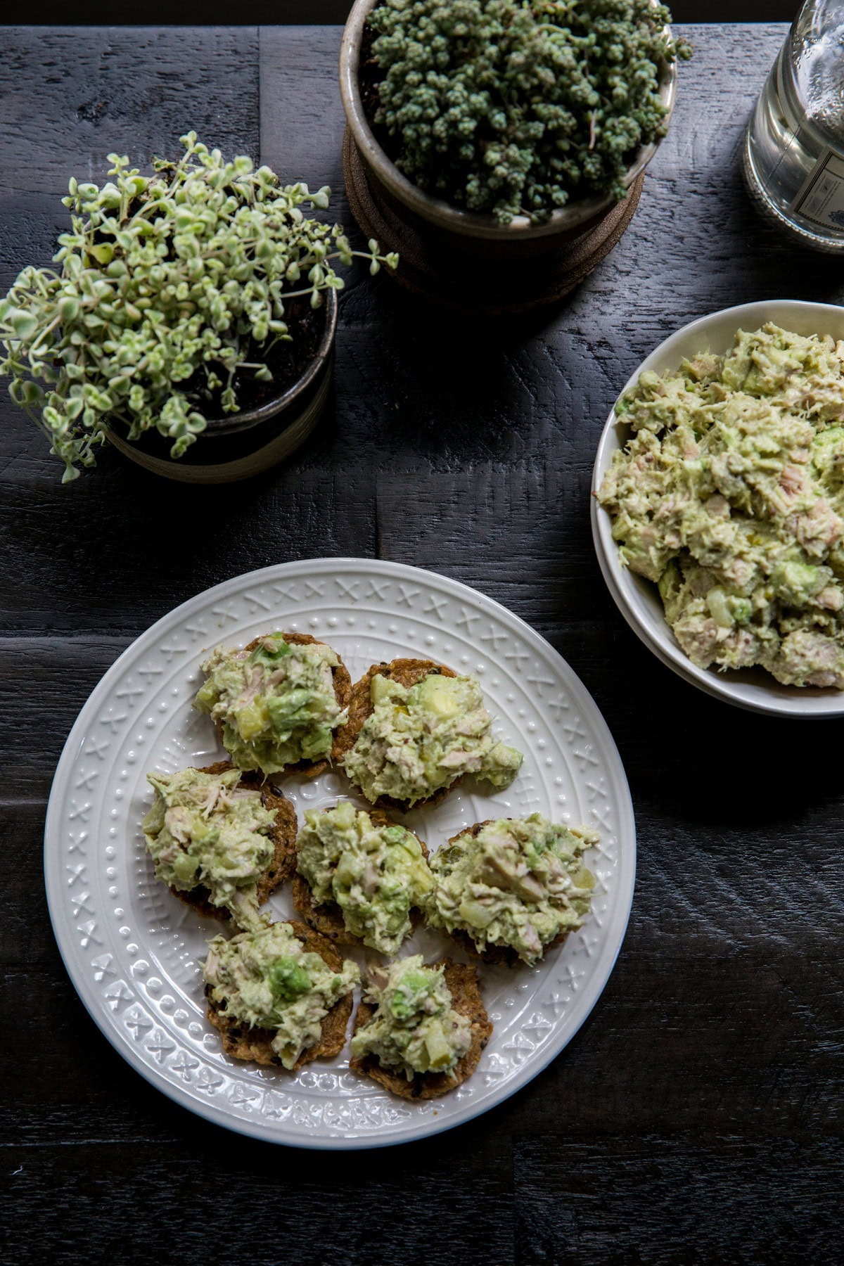 Avocado tuna salad on crackers on a plate, ready to serve.