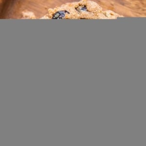Two wooden plates with blueberry muffins on each, one muffin sliced in half so you can see the fluffy inside with fresh blueberries.