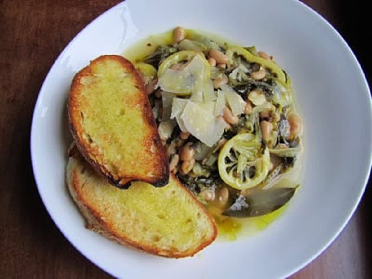 Braised Escarole and Beans with buttered toasted baguette in a large bowl.