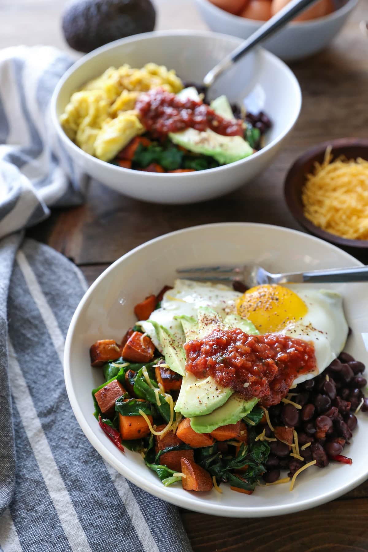large bowl full of black beans, sweet potatoes, kale, eggs, avocado, and salsa for a breakfast bowl