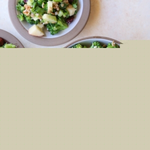 One large bowl full of broccoli salad and two little plates with broccoli salad. Ready to serve.