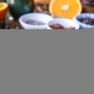Four cardamom orange cookies stacked on top of each other with nuts and chocolate in the background.