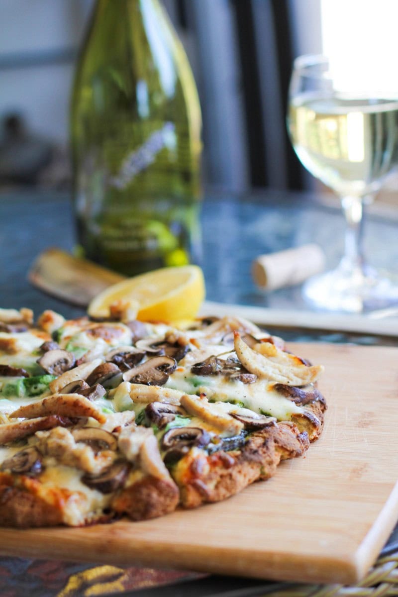 pizza with pesto sauce on a cutting board, sliced into slices.