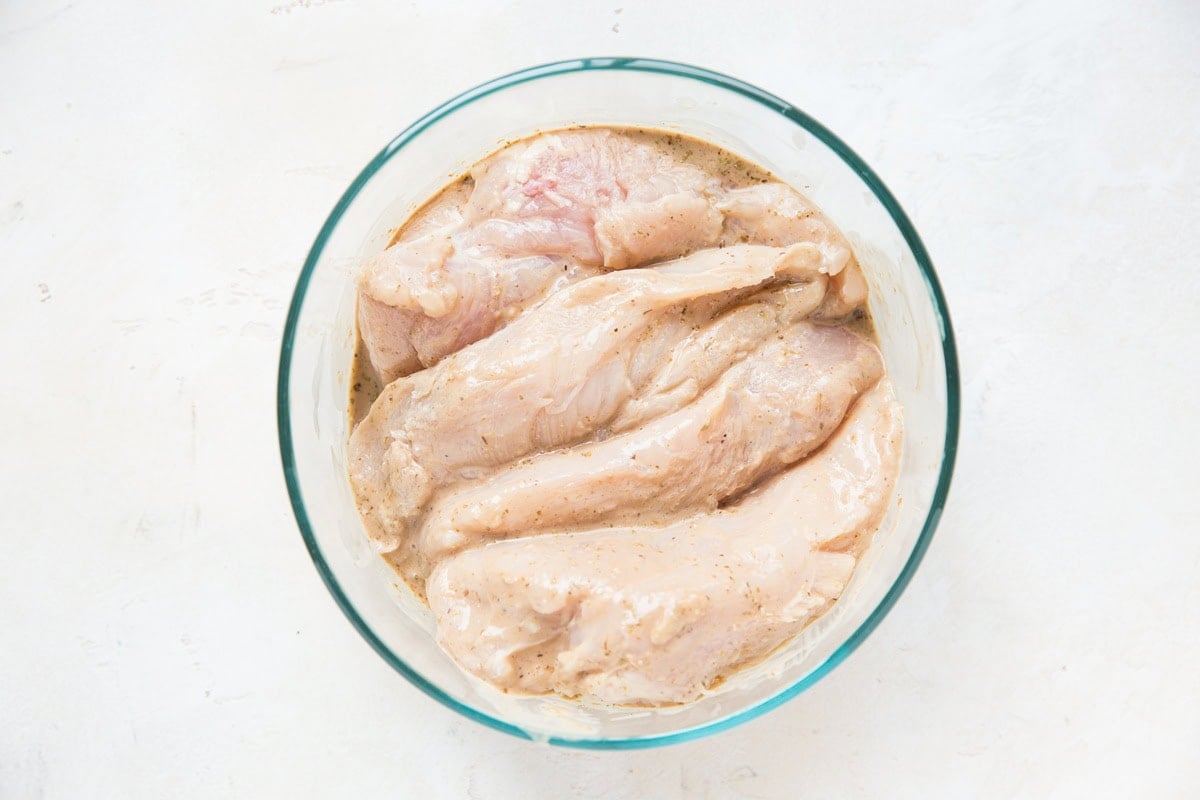 chicken saturated in balsamic marinade in a glass tupperware container, ready to go into the refrigerator to marinate.