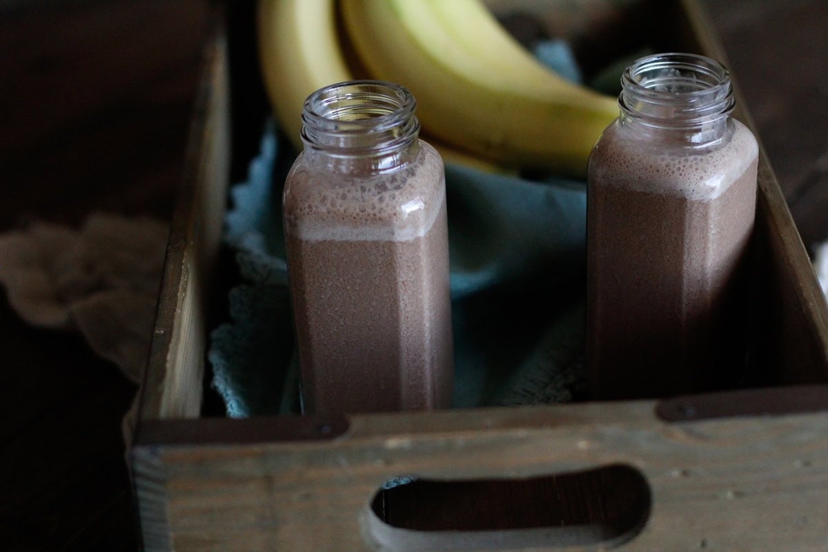 Chocolate Hemp Seed Smoothies in a wooden crate with bananas, ready to sip.