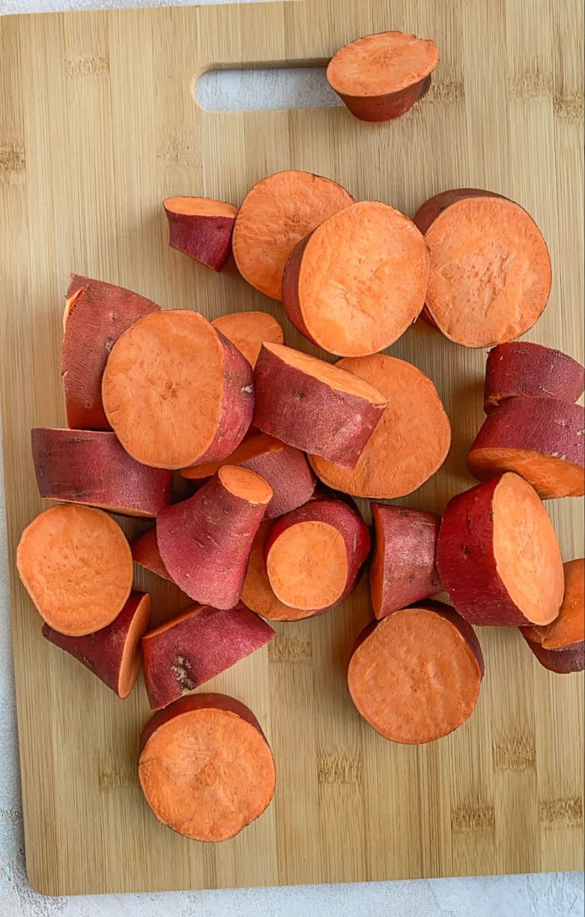 Chopped sweet potatoes on a wooden cutting board to be boiled for casserole.