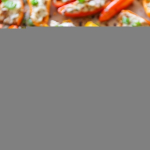 Baking sheet with cream cheese stuffed baby bell peppers on top.
