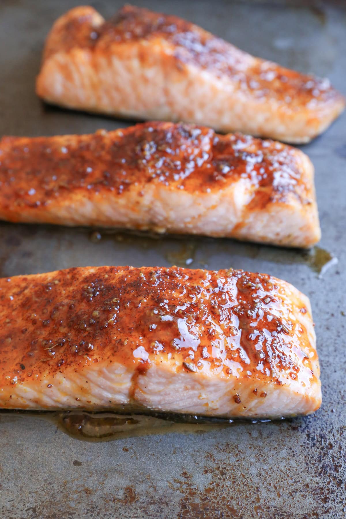 Four filets of honey glazed salmon on a sheet pan, ready to serve.
