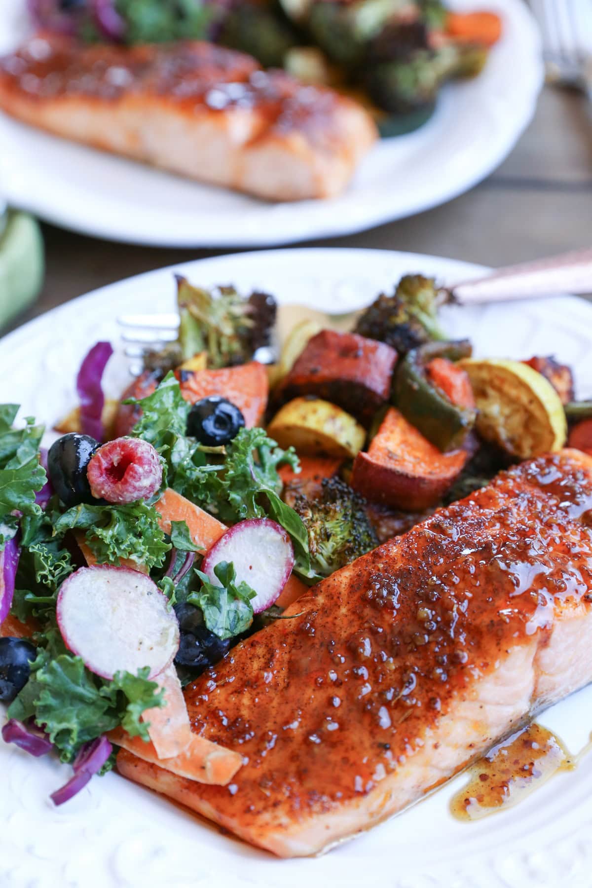 Crispy Honey-Glazed Salmon with roasted vegetables and kale salad on a plate with a fork, ready to eat.