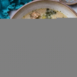 large bowl of creamy sausage and kale soup with fresh kale to the side and a spoon for eating.
