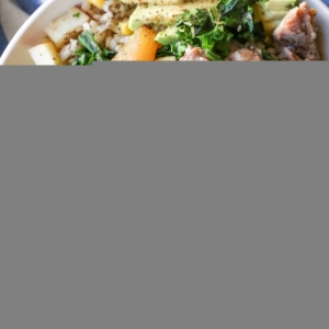 Bowl full of pulled pork, brown rice, avocado, sauteed kale and seasonings.