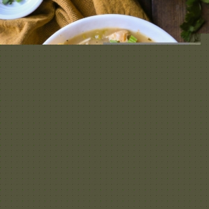 One large bowl of white chicken chili with chili toppings. A bowl of grated cheese to the side and a golden napkin.