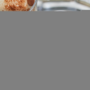 Naturally Sweetened and Dairy Free Horchata in two glasses with cinnamon sticks in the glasses and ice cubes. Sitting on a tray, ready to serve.