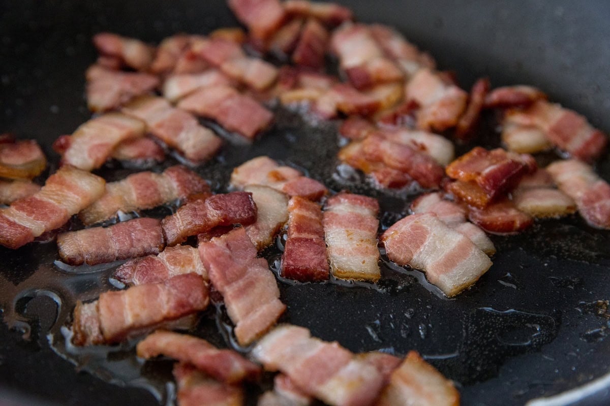 chopped bacon cooking in a skillet to crispy perfection.