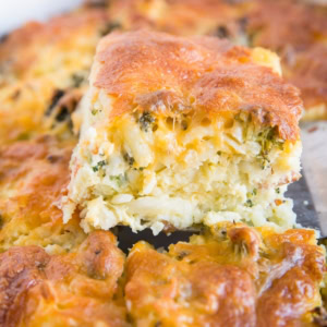Spatula pulling a slice of broccoli cheddar egg hashbrown casserole out of a casserole dish.