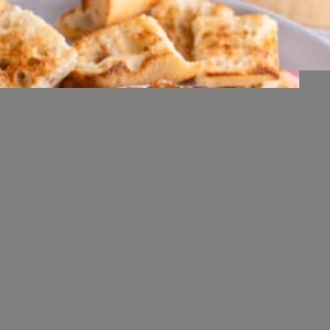 Bowl of eggplant caponata on a plate with toasted baguette, ready to serve.