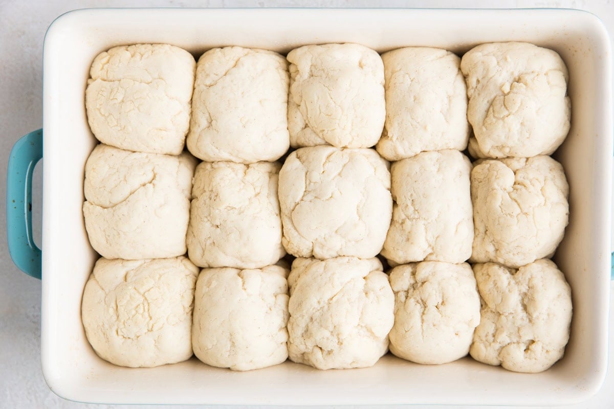 Casserole dish full of puffy dough balls to make rolls.