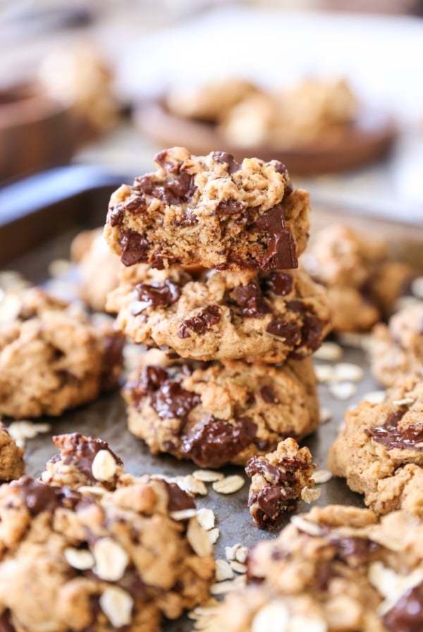 Stack of three gluten-free chocolate chip oatmeal cookies on a baking sheet with more cookies to the side.