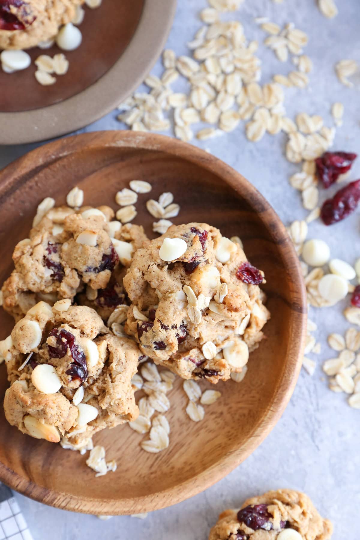 Wooden plate of gluten-free oatmeal cookies with dried cranberries, white chocolate chips and macadamia nuts.