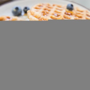 Stack of the best gluten-free waffles on a plate with butter, honey and blueberries